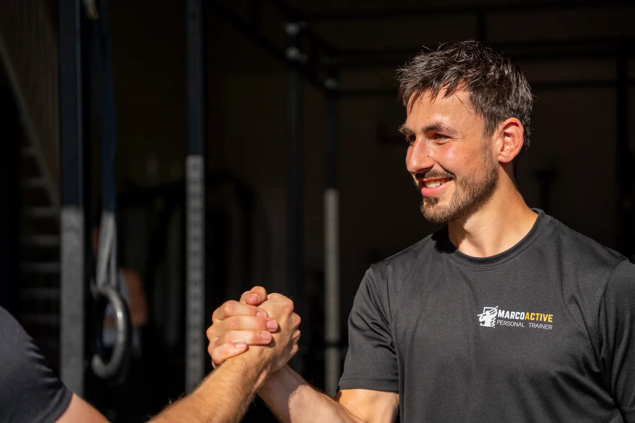 De coach van Marco Active geeft een sporter een stevige handdruk