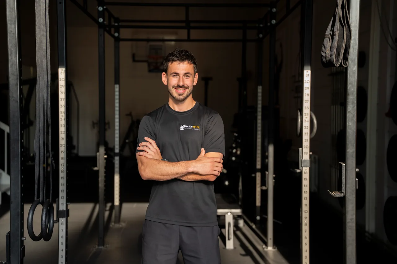 De coach van Marco Active met de armen over elkaar in de gym