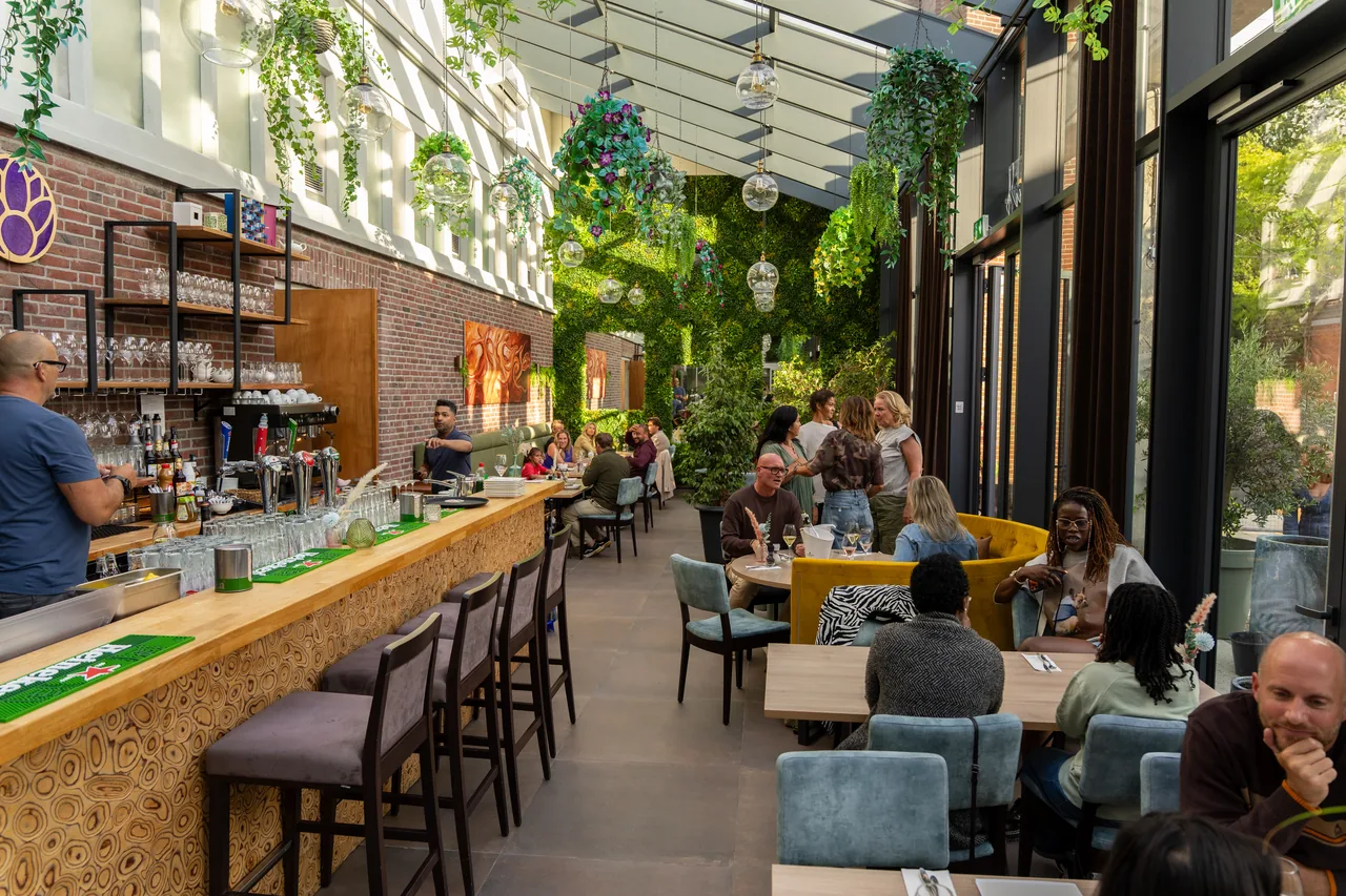 Het interieur van Brasserie Lenny, met de lange bar en veel groen